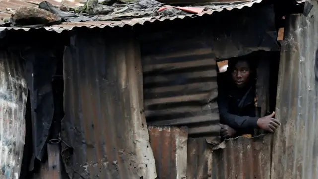 A man watches as protesters clash with riot police attempting to disperse supporters of Kenyan opposition leader Raila Odinga in Kibera slums of Nairobi. 26/10/2017