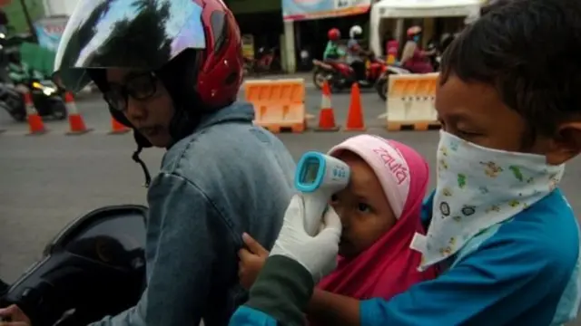 Petugas medis mengukur suhu tubuh pengendara yang masuk ke Kota Tegal (07/04).