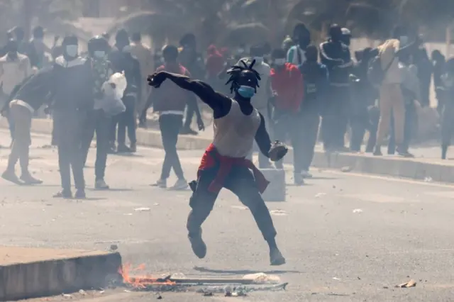 A supporter of opposition leader Ousmane Sonko hurls stones during clashes with security forces.