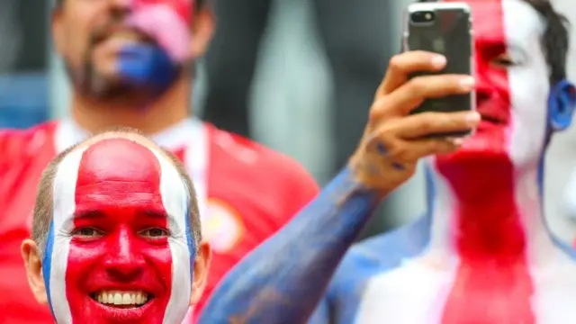 Homens com os rostos pintados com as cores da bandeira da Costa Rica, vermelho, branco e azul