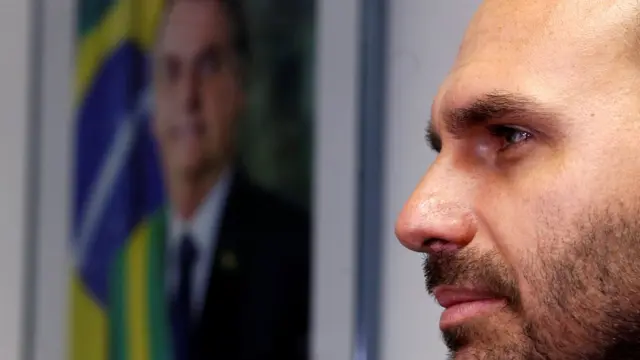 Eduardo Bolsonaro apareceall win casinoperfil com foto do pai, Jair Bolsonaro, atrás