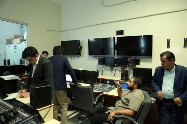 Bir RTÜK yetkilisi İMC TV stüdyolarında not alıyor.