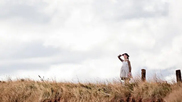 プリンスエドワード島の崖に立つエイミーベス・マクナルティ演じるアン