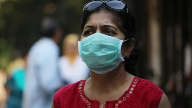 கொரோனா வைரஸ் அச்சத்தில் முக மூடி அணிந்த பெண்.