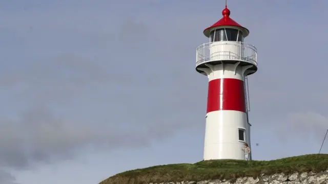Un faro blanco y rojo al borde de un acantilado en las islas