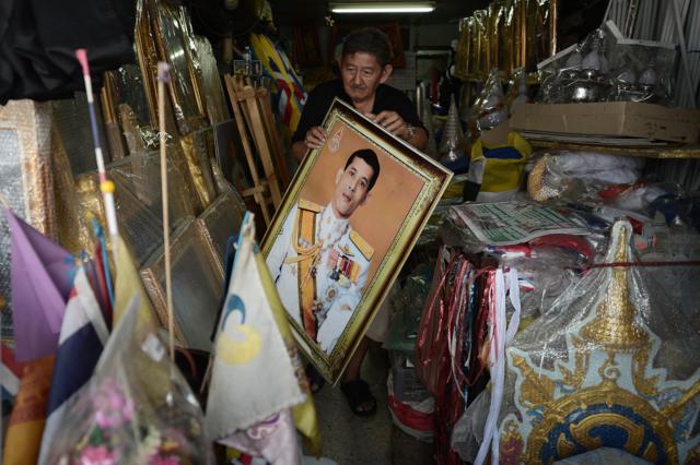 29 Nov 2016 - A vendor carries a pictures of Thailand's Crown Prince Maha Vajiralongkorn at a shop in Bangkok, Thailand.