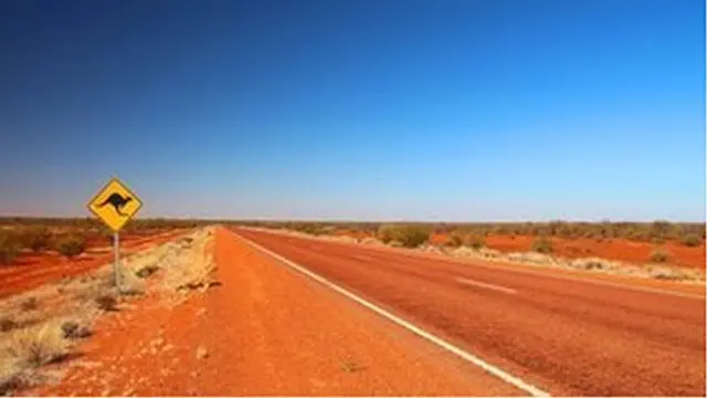 A generic photo of an Australian outback road with a kangaroo road sign
