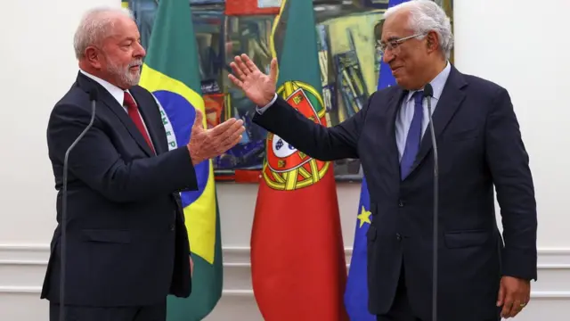 Lula e António Costa sorrindo e prestes a apertarem as mãos, na frenteganesha gold jogobandeiras