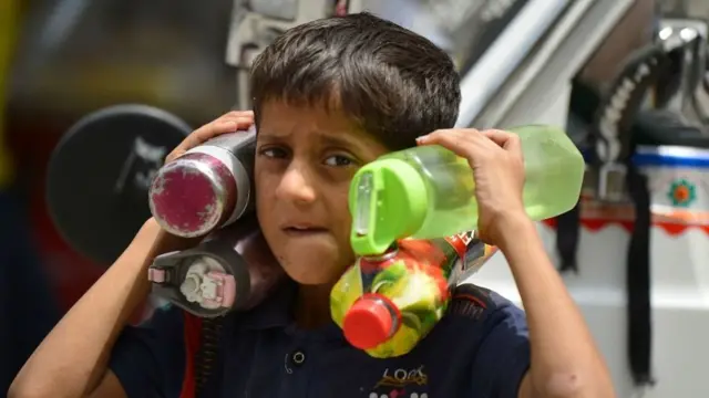 தண்ணீர் பாட்டிலை கொண்டு செல்லும் சிறுவன்