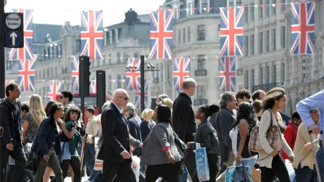 Люди йдуть по вулиці, де розвішані британські прапори