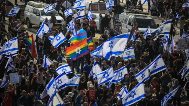 متظاهرون يرفعون الأعلام الإسرائيلية أمام مبنى الكنيست خلال مظاهرة ضد خطط الإصلاح القضائي في القدس