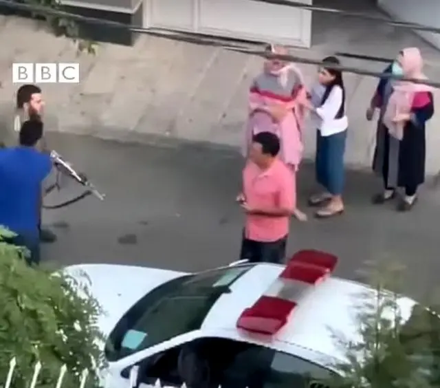 سرباز پلیس اسلحه را از ماشین بیرون می‌آورد و به سوی شهروندان می‌گیرد