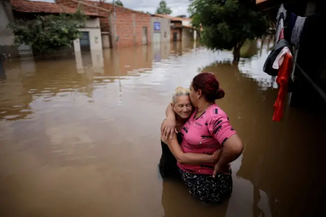 Mother and daughter embrace in a flooded street