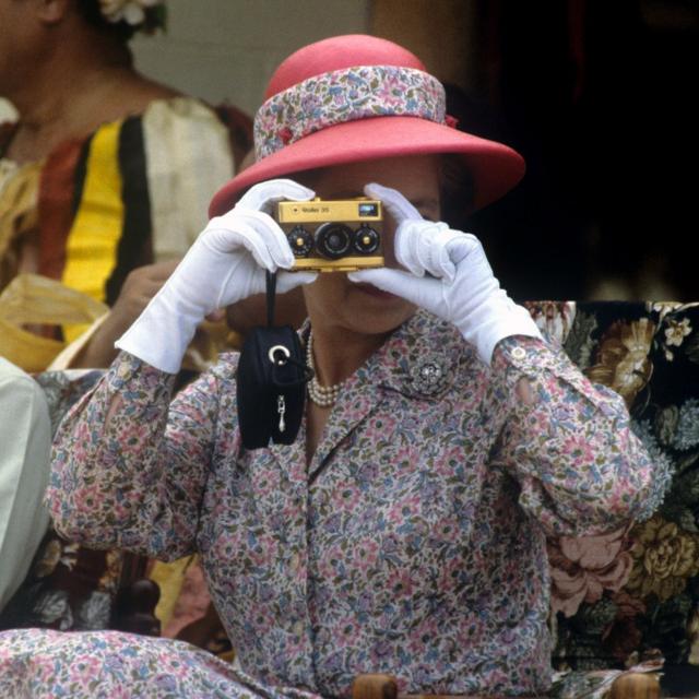 A rainha tirando fotos com sua câmera Rollei dourada