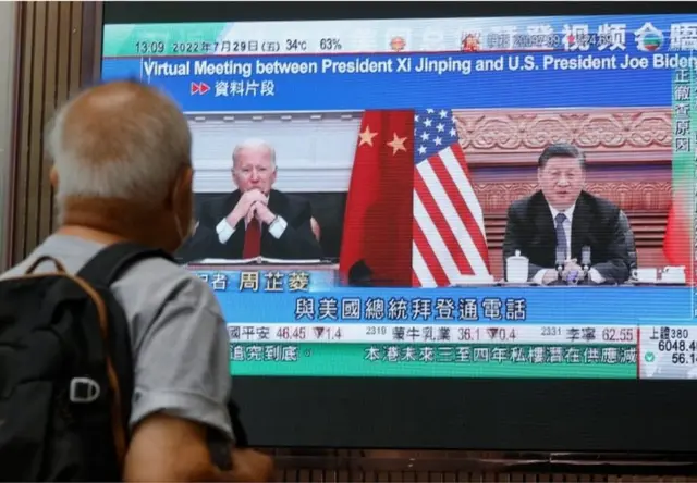 一名男子在香港一家購物中心觀看電視播出的習近平與拜登通話的新聞。