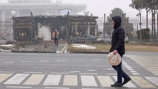 A man walks in front of a the burned out presidential building in Almaty