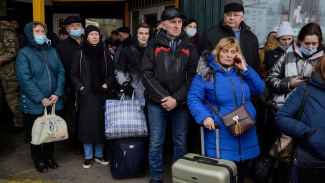 Cientos de personas hacen largas filas para tomar buses para evacuar Kiev, la capital de Ucrania.