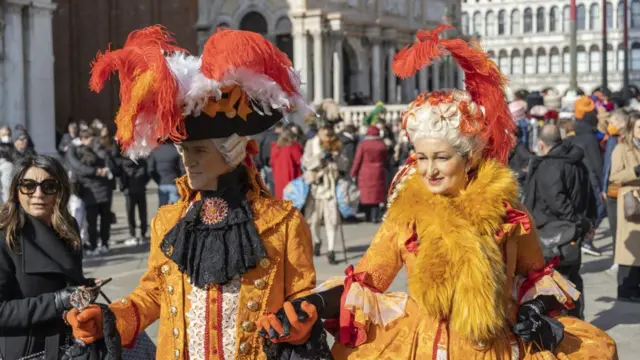 Пара в оранжевых костюмах на площади Св. Марка