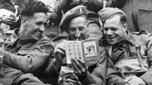 Британські солдати читають путівник Францією для туристів на борту десантного катера, що прямує до Нормандії, Ла-Манш, 1944 рік