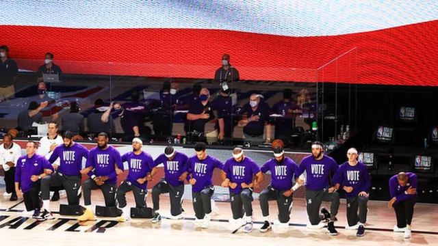 Lakers players kneel during the national anthem while wearing t-shirts emblazoned with 'vote'