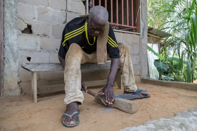 हथियार पर धार लगाता कैमरून का एक व्यक्ति