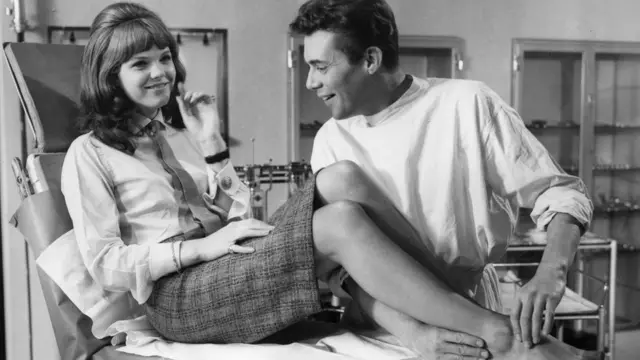 Actor Dirk Bogarde toma el pie de una actriz durante el rodaje de una película