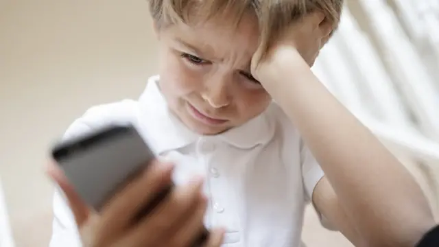 Niño llorando viendo su teléfono