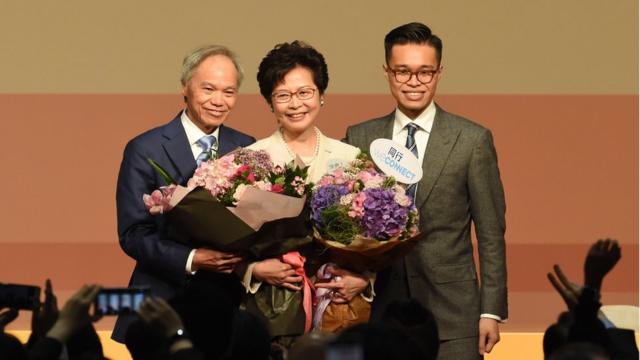 Hong Kong's new chief executive Carrie Lam (C) holds bouquets as she stands on stage after winning the Hong Kong chief executive election in Hong Kong on March 26, 2017.