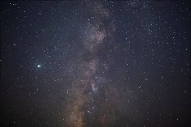 A meteor streaks past stars in the night sky during the annual Perseid meteor shower.
