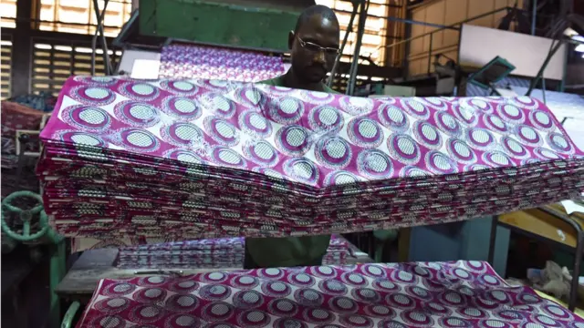 Un employé plie des pagnes dans une ligne de production de l'usine Uniwax à Abidjan, le 6 septembre 2016.