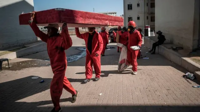 Members of the Red Ants carry a mattress on their heads during a joint eviction operation between the Red Ants and the South African Police Service (SAPS) of people that illegally occupied apartment buildings in Roodepoort, near Johannesburg, on August 25, 2020.