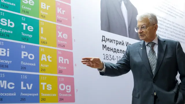Yuri Oganessian frente a una gran tabla periódica