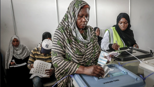 Obìnrin tó fi ìbòrí sórí, tó ń fi ìbò rẹ̀ sínú àpótí ìbò 