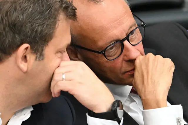 Almanya Başbakanı Friedrich Merz bütçe görüşmeleri sırasında biriyle konuşuyor. Yakın plan.