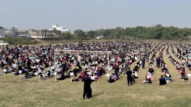 सुनसरीमा निर्वाचन प्रहरीका छनोट कार्यक्रम चल्दाको दृश्य। खेलमैदानमा सैयौँ युवाहरू बसेर परीक्षामा सहभागी भएको देखिन्छ