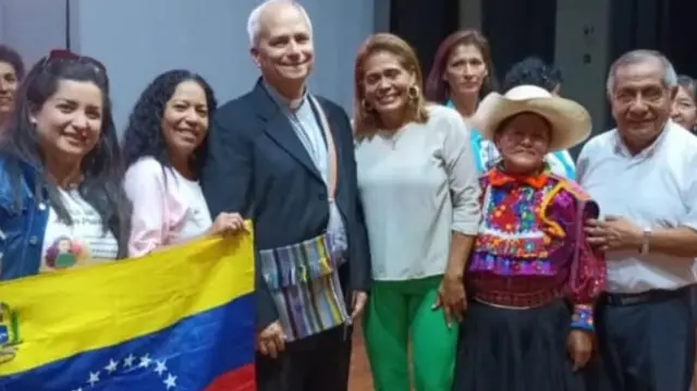 Lisbeth Díaz, junto al entonces obispor Robert Prevost y una bandera venezolana.