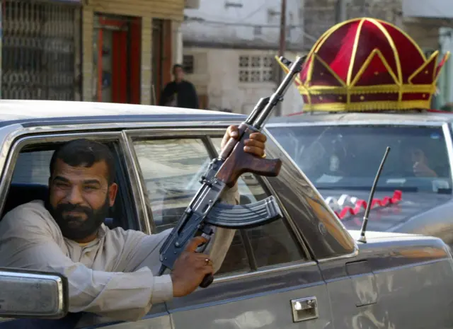 A man leaning out of a car fires into the air