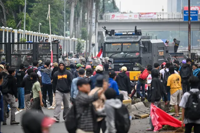 Personel polisi menghalau pengunjuk rasa di Jalan Letjend S Parman, depan Gedung DPR, Jakarta, Senin (25/08).