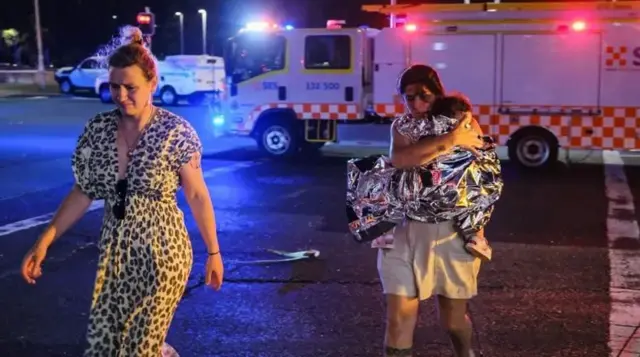 مادری در صحنه تیراندازی که کودکش را در آغوش دارد. 