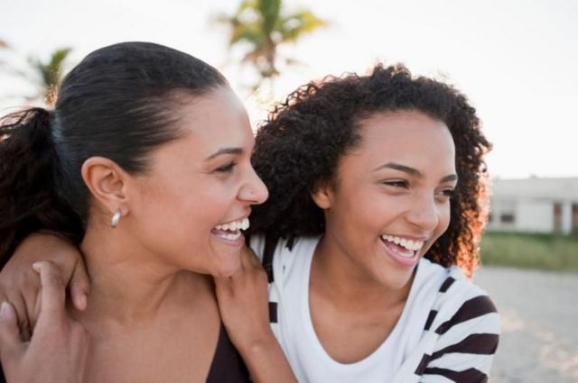 Mulher adulta e adolescente negras sorriem