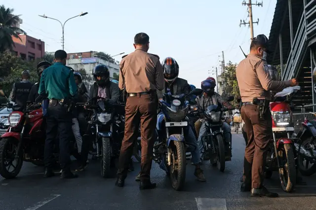 মোটরসাইকেল আরোহীদের জিজ্ঞাসাবাদ করছেন পুলিশের কয়েকজন সদস্য