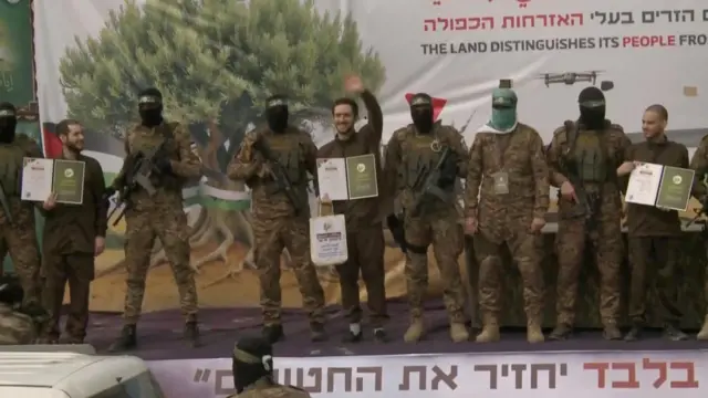 ハマスに解放されたイスラエル人3人は、ハマス戦闘員に囲まれて壇上に並ばされた（22日、ガザ地区中部ヌセイラト）