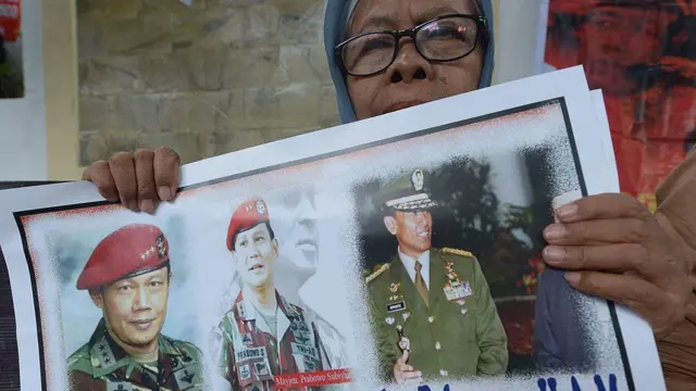 Seorang pengunjuk rasa Indonesia memegang plakat yang bertuliskan "Pelaku penculikan, pembunuhan dan pelanggar hak asasi manusia".