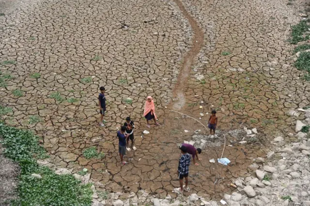 Anak-anak bermain di dekat dasar kering sebuah danau di kota Kathiatoli, Distrik Nagaon, Assam, India, pada 20 April 2024.