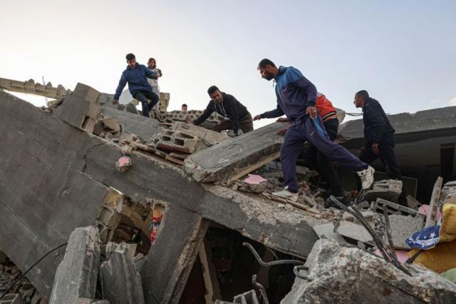 Homens palestinos revistam escombros após ataque aéreo israelense em Rafah, em 3 de março
