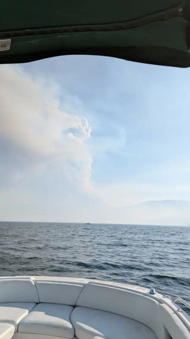 ボートから湖と空を撮影した写真。青い空に、写真左手から白い煙が広がっている