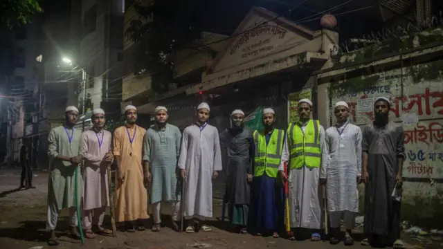 ढाका में एक मंदिर की सुरक्षा के लिए रात में पहरा देते मदरसा छात्र. पुलिस थानों में नहीं है और ऐसे में नागिरक समितियां निगरानी का काम कर रही हैं. 