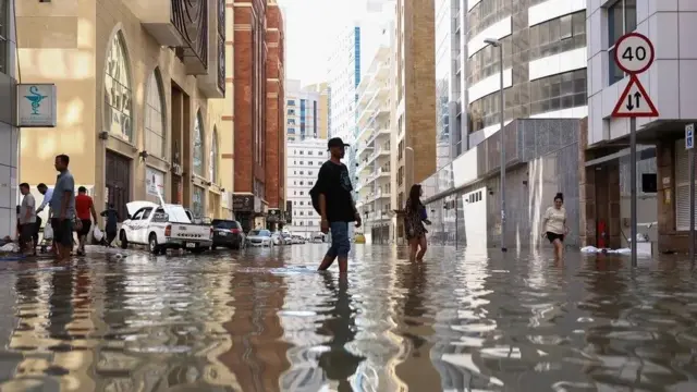 Pessoas caminham pelas ruas alagadasdicas de aposta em futeboldecorrência das enchentes causadas pelas fortes chuvasdicas de aposta em futebolDubai