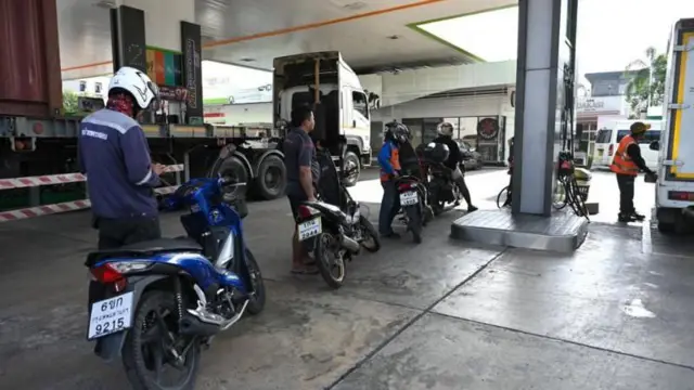 Motorcyclists waiting to use a petrol pump on a fuel station concourse.