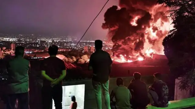 Watu wakitazama moto kutoka bohari ya mafuta ya Shahran mjini Tehran siku ya Jumatatu baada ya Israel kuishambulia.